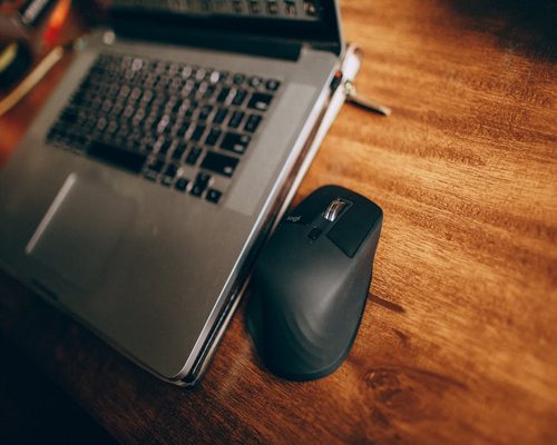 A laptop station set up with adequate peripheral spacing on a wooden table, representing ergonomic device usage